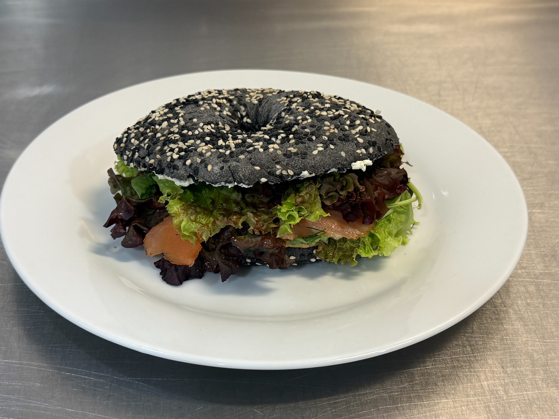 Plněný bagel se sezamem, uvnitř plátky šunky a sýra